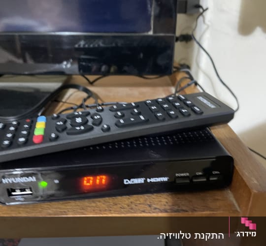 שלט רחוק וממיר דיגיטלי על מדף עץ